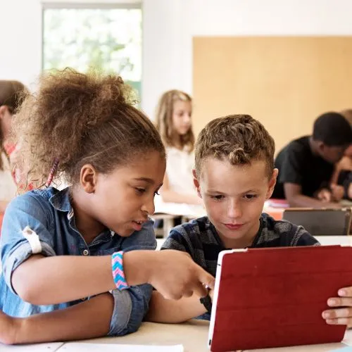 Estudiantes en un aula moderna con laptops y Smart TV